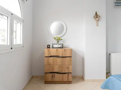 a bedroom with a mirror and a wooden dresser at Yellow house in Palaiá Fókaia