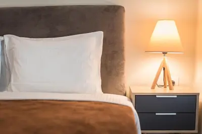 a bed with a white pillow and a lamp on a night stand at Exeptional Apartment in Athens