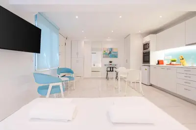a kitchen with white cabinets and blue chairs at Cute and Convenient Studio in Athens Center in Athens