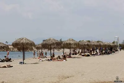 a group of people on a beach with straw umbrellas at Modern & Classy Central Apartment in Athens