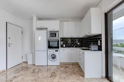 a white kitchen with a washer and dryer at Varkiza by the sea in Vari