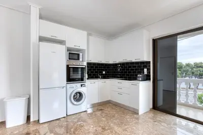 a kitchen with white cabinets and a washer and dryer at Varkiza by the sea in Vari