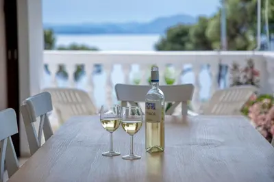a bottle of wine and two wine glasses on a table at Varkiza by the sea in Vari
