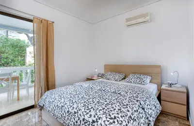 a bedroom with a black and white bed and a window at Varkiza by the sea in Vari