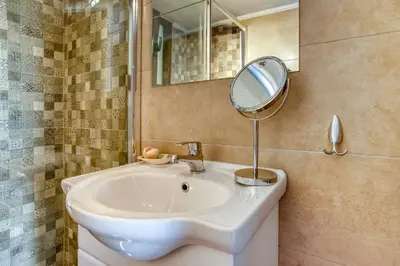 a bathroom with a white sink and a mirror at Varkiza by the sea in Vari