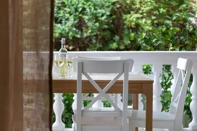 a table with two white chairs and a bottle of wine at Varkiza by the sea in Vari