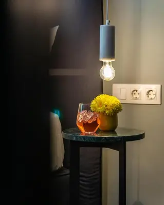 a table with a vase of flowers and a lamp at PAME Paradiso in Athens