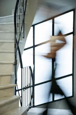 a person walking down a staircase with a shadow at PAME Paradiso in Athens