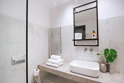 a white bathroom with a sink and a mirror at PAME Paradiso in Athens