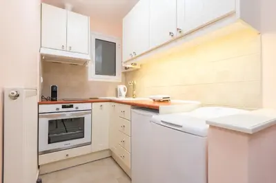 a white kitchen with white cabinets and a sink at Thissio Cocoon in Athens