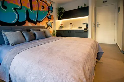 a bedroom with a large bed and a kitchen at Triple A - Graffiti Homage in Psirri Square - FREE Parking! in Athens