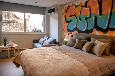 a bedroom with a large bed with a painting on the wall at Triple A - Graffiti Homage in Psirri Square - FREE Parking! in Athens
