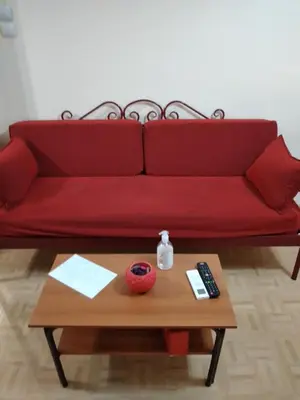 a red couch with a table and a remote control at Perikleous Apartment in Athens