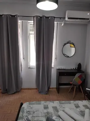 a bedroom with gray curtains and a table and a mirror at Perikleous Apartment in Athens