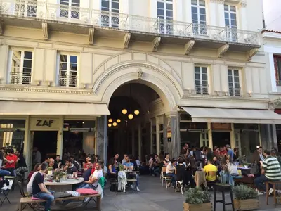 a group of people sitting at tables outside of a building at Perikleous Apartment in Athens