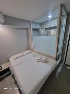 a bedroom with a large window with two shoes on a bed at athens.apartotel.box in Athens