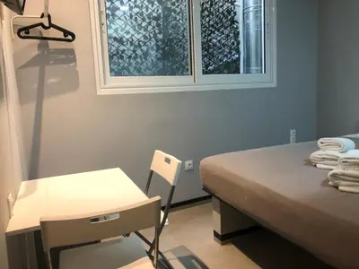 a bedroom with a bed and a desk and a window at athens.apartotel.box in Athens
