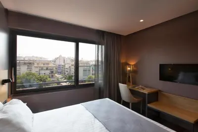a hotel room with a bed and a desk and a window at City Lights Athens by YHA in Athens