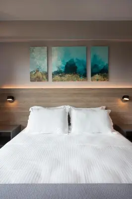 a bedroom with a white bed with four paintings on the wall at City Lights Athens by YHA in Athens