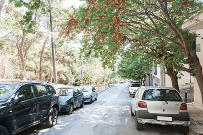 a row of cars parked on a street with trees at Peaceful 2BD Apartment in Kolonaki by UPSTREET in Athens