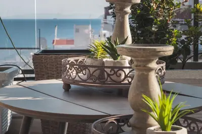 a table with a fountain and potted plants on a balcony at Sea view super romantic apartment in Athens