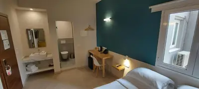 a bedroom with a bed and a bathroom with a sink at The Convo Athens Riviera in Athens