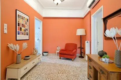 a living room with orange walls and a red chair at Art in Athens Suite in Athens
