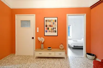 an orange room with a table and a door at Art in Athens Suite in Athens