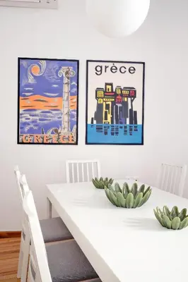 a white dining room table with three posters on the wall at Art in Athens Suite in Athens