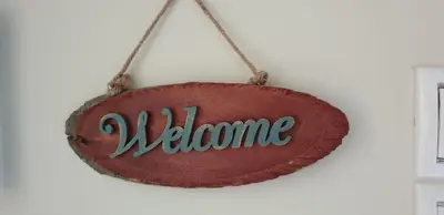 a wooden sign with the word welcome hanging on a wall at Cozy Little Home in Athens