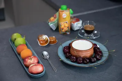 a table with a plate of fruit and a bowl of yogurt at Olygreen Athens Residences in Athens