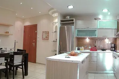 a kitchen with a refrigerator and a table with chairs at A1 Elegant Vouliagmeni apt in a Unique Spot in Athens