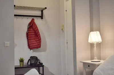 a red coat hanging on a wall next to a bed at Check Point - Acropolis in Athens