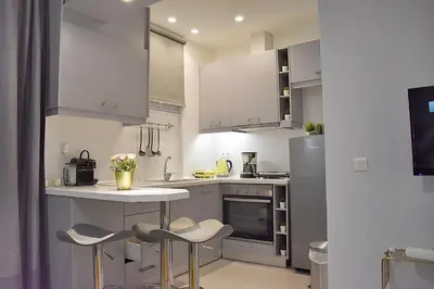 a kitchen with white cabinets and a table and stools at Check Point - Acropolis in Athens