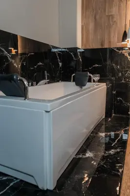 a white bath tub in a bathroom with black marble at NOHO Boutique , premium living Dikeou 8 in Athens
