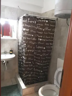 a bathroom with a shower curtain with writing on it at House in the center of Piraeus next to the port and the metro!! in Piraeus