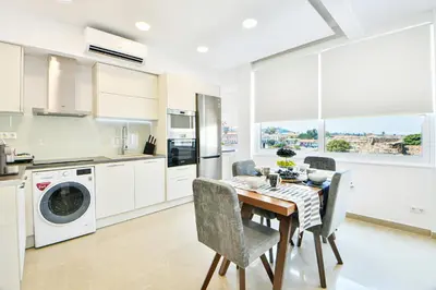 a kitchen with a table and chairs and a kitchen with white cabinets at AEOLIS SUITES in Athens