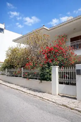 a fence in front of a house with red flowers at Apartment in Peania (15min from Airport) in Paianía