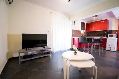a living room with a tv and a table and a kitchen at SEASIDE SUNSET WALKS in Athens