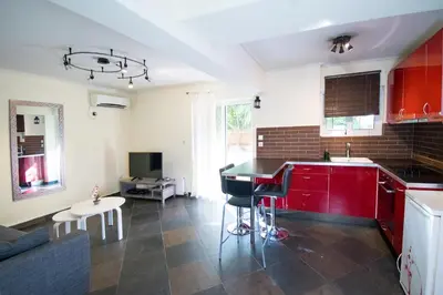 a kitchen with red cabinets and a living room at SEASIDE SUNSET WALKS in Athens