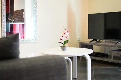 a living room with a white table and a tv at SEASIDE SUNSET WALKS in Athens