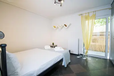 a white bedroom with a bed and a window at SEASIDE SUNSET WALKS in Athens