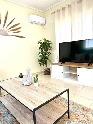a living room with a coffee table and a flat screen tv at Bohem Apartment near Athens Airport in Spáta