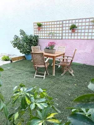 a table and chairs and a pink wall with plants at Bohem Apartment near Athens Airport in Spáta