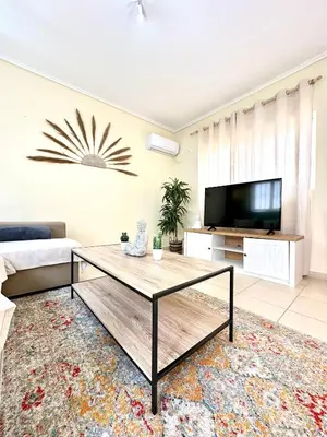 a living room with a coffee table and a tv at Bohem Apartment near Athens Airport in Spáta