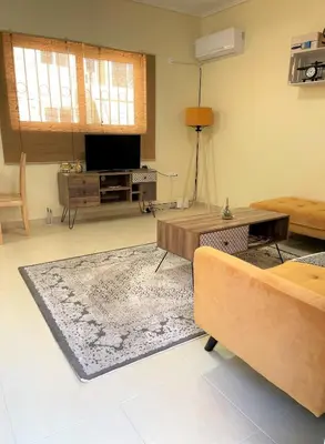 a living room with a couch and a television at Boho Apartment near Athens Airport in Spáta