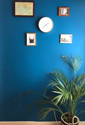 a blue wall with a clock and a potted plant at Boho Apartment near Athens Airport in Spáta