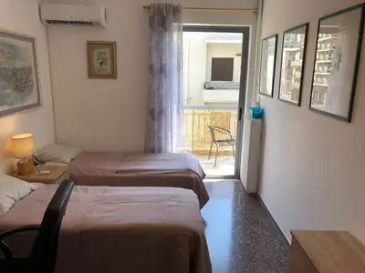 a room with two beds and a door to a balcony at Metaxourgio spacious two bedroom apartment in Athens