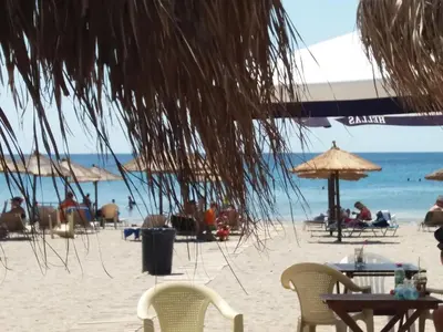 a beach with chairs and umbrellas and people on the beach at Painter's house by the beach in Athens