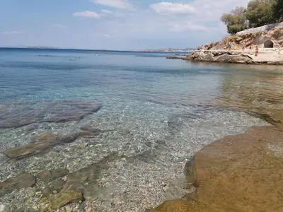 a beach with clear water and a rocky shore at Painter's house by the beach in Athens